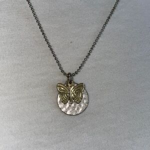 Gold butterfly pendant necklace with round silver pendant that says “Imagine”